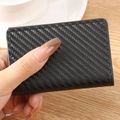 Porte-cartes en cuir noir à texture fibre de carbone tenu à la main dans un cadre de bureau - Texture Fibre de Carbone-Noir