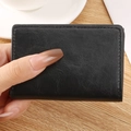 Porte-cartes de visite compact en cuir noir à motif litchi tenu sur une table en bois - PU-Noir