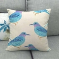 Dettaglio della fodera per cuscino in lino con stampa di uccelli su divano grigio - 45x45cm / Motivo Gruppo di Uccelli Blu (4)