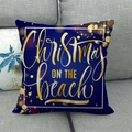 Housse de coussin de Noël en lin bleu marine avec imprimé doré sur un canapé gris - Christmas On The Beach Blue (14)