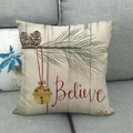 Dettaglio di federa per cuscino in lino con pigne e testo Believe su un divano - Stile Campana Believe / Nuovo 2