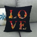 Funda de cojín de lino con letras LOVE y diseño floral de acuarela en sofá gris - Negro (3)