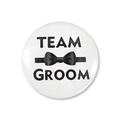 Dettaglio della spilla tonda Team Groom in latta con papillon nero per matrimoni - Team Sposo Bianco