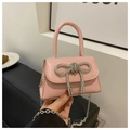Detail shot of a pink crossbody bag featuring a sparkling rhinestone bow and silver chain - Pink