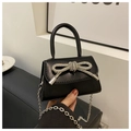 Close-up of black crossbody bag featuring a large silver rhinestone bow and chain strap - Black
