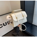 Close-up of white crossbody bag with gold hardware and a cute white monster plush charm - With Charm / Off White