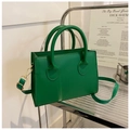 Detailed view of green leather handbag on a silver stand with adjustable shoulder strap - Green