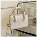 Detalle de un bolso bandolera minimalista en color crema con costuras y herrajes dorados - Blanco