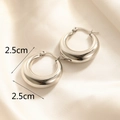 Dettaglio orecchini a cerchio in acciaio lucido da 2,5 cm su sfondo in raso beige - Stile Cerchio Lucido (E136)