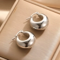 Orecchini a cerchio spessi in argento lucido presentati su velluto beige lussuoso - Stile Semicerchio Gonfio (E135)