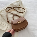 Bolso tipo montura marrón de cuero sintético con hebilla dorada sobre traje blanco - Marrón