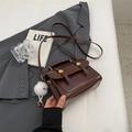 Retro dark brown crossbody bag with top handle and plush charm on a grey blazer - With Pendant / Brown