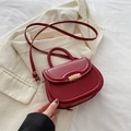 Bolso vintage rojo oscuro con hebilla en espiral dorada sobre fondo blazer beige - Rojo