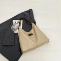 Minimalistische beige Shopper-Tasche mit braunen Trägern auf grauem Blazer-Hintergrund - Gebrochenes Weiß
