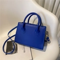 Borsa a mano quadrata minimalista blu reale in pelle liscia con tracolla su sedia bianca - Blu