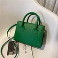 Minimalist green rectangle crossbody bag with gold hooks on a minimalist white chair - Green