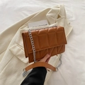 Brown quilted crossbody bag with silver chain strap on an off-white blazer coat - Brown