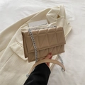 Chic beige quilted crossbody bag with silver chain strap shown in a minimalist setting - Khaki