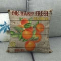 Detail eines Vintage-Leinen-Kissenbezugs mit Orangenmotiv auf einem grauen Sofa - Orangen-Stil