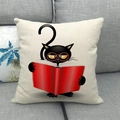 Close-up of a cartoon black cat with red glasses reading on a beige linen pillowcase - Black Cat With Glasses Reading Book (5)