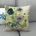 Detalle de funda de cojín de lino con flores y texto HOPE sobre sofá elegante - Amapola Azul Violeta (HOPE) / 45x45cm