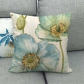 Detail eines blaugrünen Kissenbezugs aus Leinen mit Aquarellblumen auf grauem Sofa - Seeblaues Mohn (4)