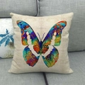 Funda de cojín de lino con estampado de mariposa abstracta sobre un sofá gris neutro - Mariposa Splash de Colores (1)
