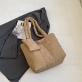 Bolso tote acolchado caqui con monedero a juego sobre fondo de chaqueta gris - Caqui