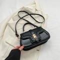Schicke schwarze Umhängetasche mit goldenem Drehverschluss auf elegantem Blazer - Schwarz