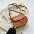 Elegant caramel brown leather saddle bag with gold ring buckle on beige blazer - Brown