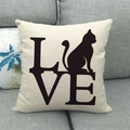 Detail eines Leinenkissenbezugs mit LOVE-Text und Katzen-Silhouette auf grauem Sofa - Künstlerisches LOVE Gestapelte Katze (5)
