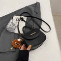 Black litchi grain faux leather saddle bag with gold metal trim and plush monster charm - With Pendant / Black