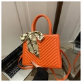 Détail d'un sac bandoulière orange matelassé avec poignée en ruban de soie chic - Orange