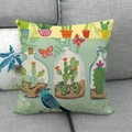 Federa decorativa in lino con uccelli verdi e stampe botaniche su un divano grigio - Stile Uccello Cactus (1)