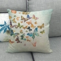 Federa in lino con motivo a farfalla ad acquerello su un divano in tessuto grigio - Colonia di Farfalle Colorate