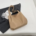 Bolso tote minimalista de cuero sintético marrón claro sobre una chaqueta gris suave - Caqui