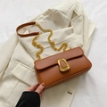 Borsa a tracolla marrone minimalista con catena dorata su sfondo blazer bianco - Marrone