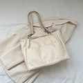 Minimalist cream leather tote bag with silver chain straps on a stylish linen background - White