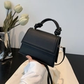 Bolso de mano negro de cuero con asa anudada y correa metálica en un estilo moderno - Negro