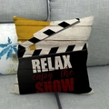 Close-up of movie clapperboard pillow cover with Relax Enjoy the Show print on sofa - Clapperboard Style
