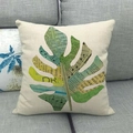 Federa per cuscino in lino con stampa a foglia di ananas su un divano grigio - Foglia di Monstera Stile Collage (Stile 12)