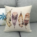 Detail of linen pillowcase featuring artistic watercolor feathers on a gray fabric sofa - 45x45cm / Light Yellow And Lavender Four Feathers (11)