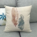 Close-up of linen pillowcase featuring two watercolor feathers on a grey sofa - 45x45cm / Brown And Gray Double Feathers (5)