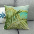 Close-up of tropical palm leaf print on linen cushion cover placed on a gray fabric sofa - 18x18 Inch / Blue Sky Palm Leaf Scenery (8)
