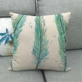Linen cushion cover with three blue artistic feathers on a grey fabric sofa - Teal And Blue Triple Feathers (4)