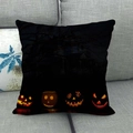 Close-up of Halloween linen pillowcase with pumpkin and bat prints on a grey sofa - Four Pumpkin Faces