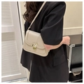Detail of grey leather crossbody bag featuring a golden bunny ear clasp on a black blazer - White