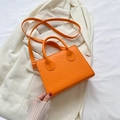Chic orange crocodile-patterned crossbody bag on a white blazer background - Orange