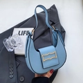 Chic light blue hobo bag with gold metal buckle on a stylish dark gray blazer - Blue