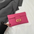 Rosafarbene Leder-Umschlagtasche mit strukturierter goldener Metallschnalle auf grauem Blazer - Rosenrosa